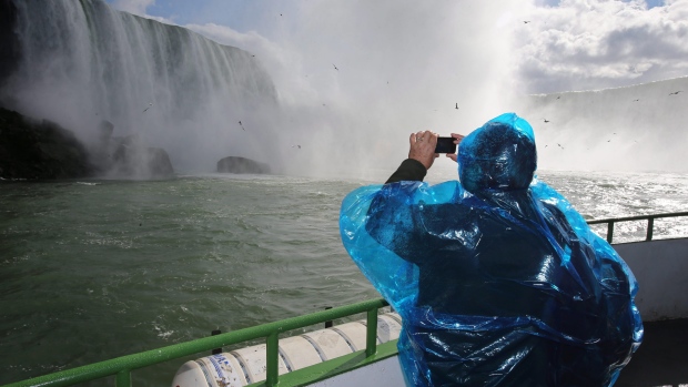 A tourist takes photos from the top deck of the Maid of the Mist in Niagara Falls, Ont., one of Canada's most popular tourist sites. Travel overal to Canada overall, however, is in decline, according to a new report. (Charles Lewis/Associated Press)